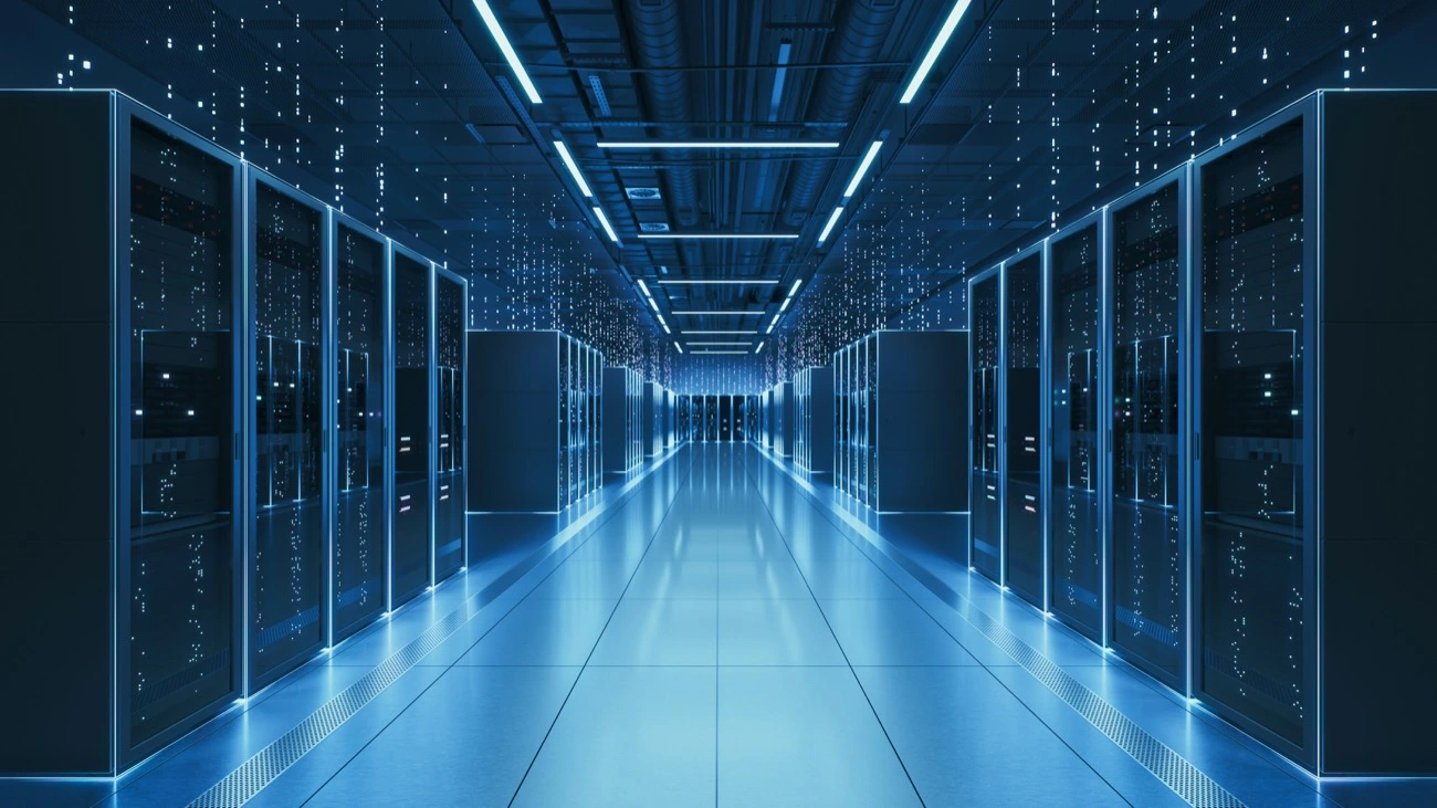 Rows of server racks lining a blue-lit central aisle in a data center.